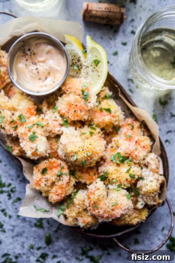 Close-up shot of perfectly baked Hot Honey Coconut Shrimp on a baking sheet, glistening with hot honey sauce.