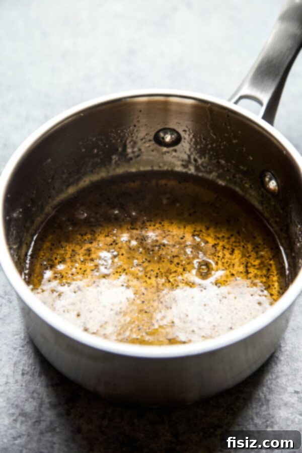 Saucepan with hot honey mixture simmering gently on the stove, radiating warmth and aromatic spices.