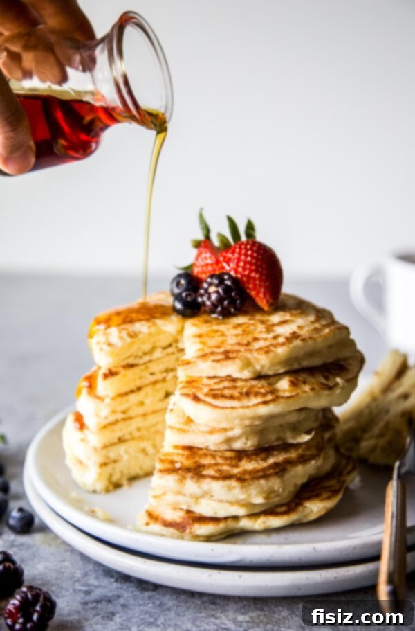 Cloud-Like Soufflé Pancakes with Fresh Berries 2 A tall stack of golden brown soufflé pancakes topped with fresh mixed berries and maple syrup