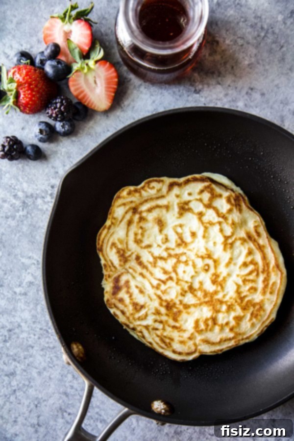 Cloud-Like Soufflé Pancakes with Fresh Berries 5 A soufflé pancake cooking in a hot skillet, gently browning on the bottom