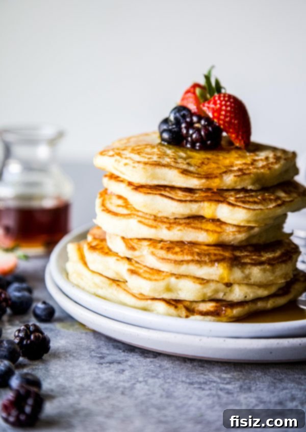 Cloud-Like Soufflé Pancakes with Fresh Berries 7 A beautifully plated serving of soufflé pancakes, garnished with fresh mixed berries and maple syrup