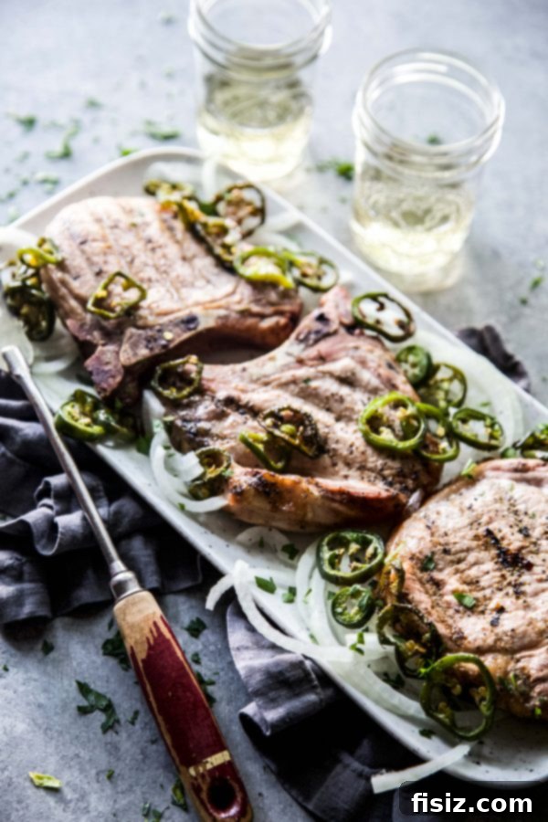 Jalapeno Infused Grilled Pork Chops 6 Juicy, grilled bone-in pork chop with a perfectly seared crust, resting on a cutting board.