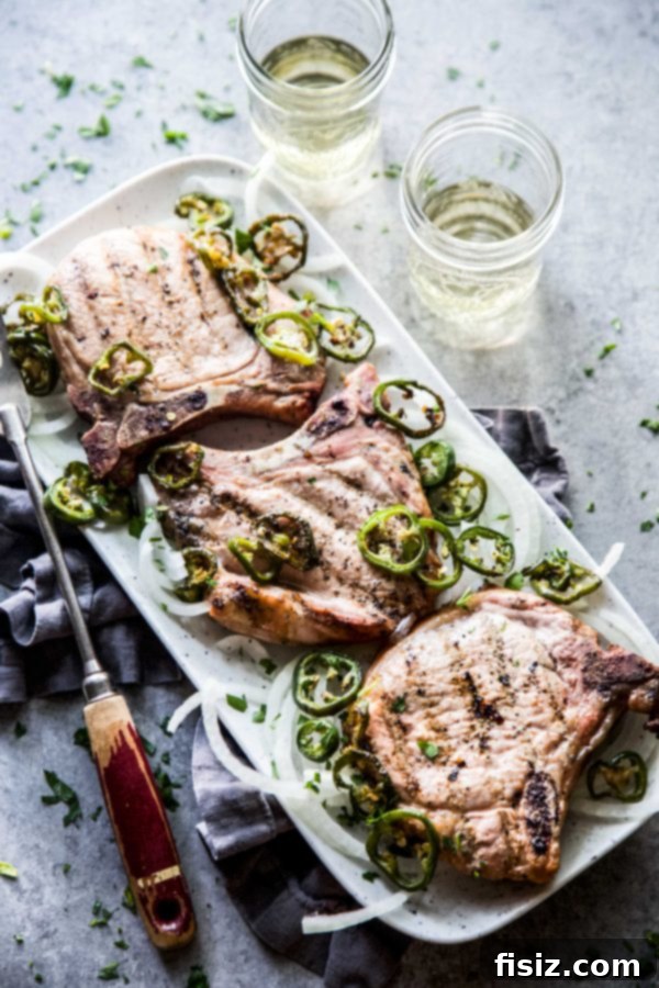 Jalapeno Infused Grilled Pork Chops 7 A beautifully presented serving of Jalapeno-Marinated Grilled Pork Chops garnished with fresh white onion slices and grilled jalapenos.