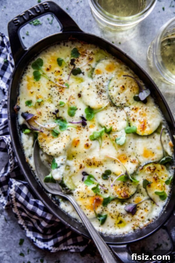Guilt-Free Cheesy Zucchini Gratin 5 Baked Cheesy Scalloped Zucchini in a casserole dish with a serving spoon.