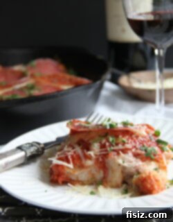 Baked Chicken Parmesan with Salami served in a cast iron skillet.