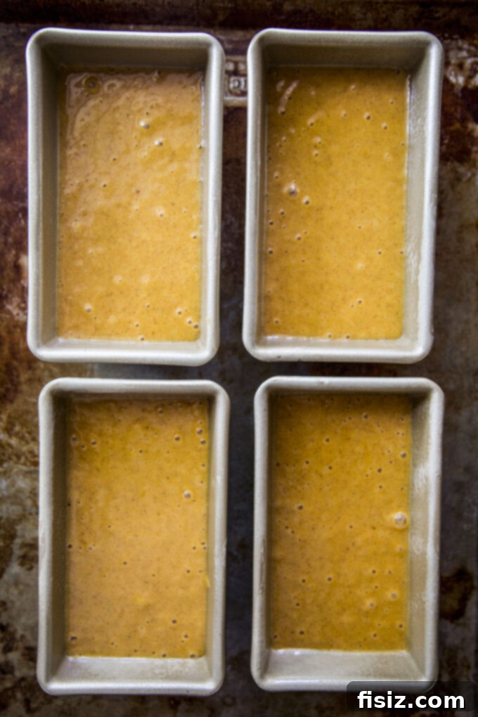 Decadent Chocolate Pumpkin Loaf 5 Four loaf pans filled with pumpkin bread batter, ready for the oven.