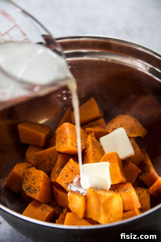 Pouring cream into a bowl of mashed sweet potatoes