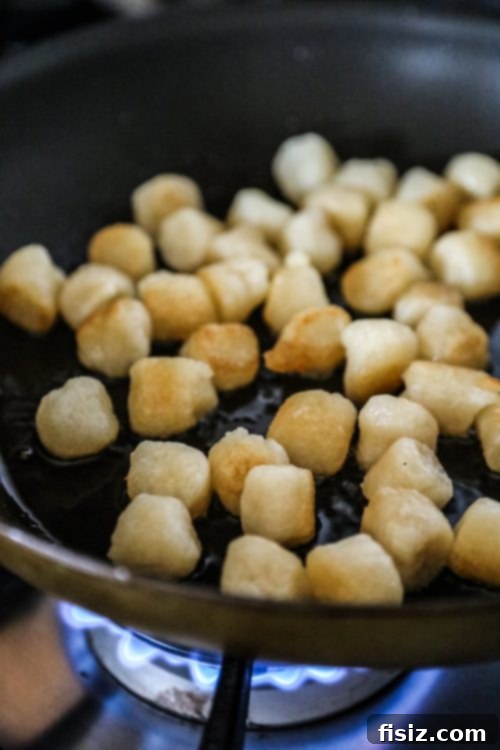 Golden Cauliflower Gnocchi with Creamy Cacio e Pepe and Perfectly Crispy Prosciutto 6 cauliflower gnocchi cooking in a skillet