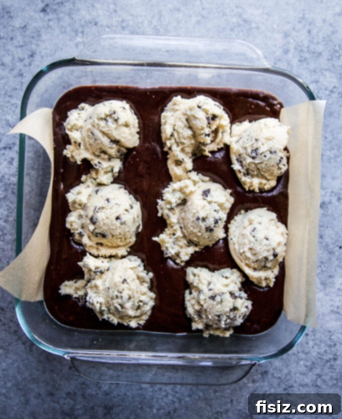 Unbaked brookie dough in a baking pan, showing the brownie and cookie layers