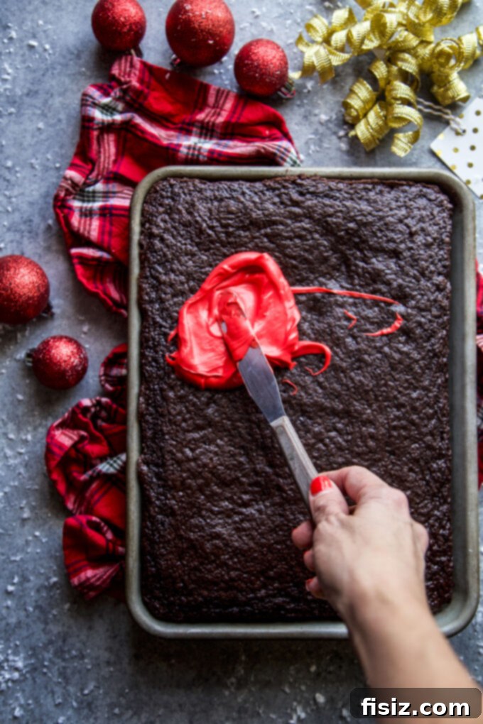 Ugly Sweater Chocolate Cake Extravaganza 5 Chocolate sheet cake being frosted evenly with a spatula, showing a smooth surface.