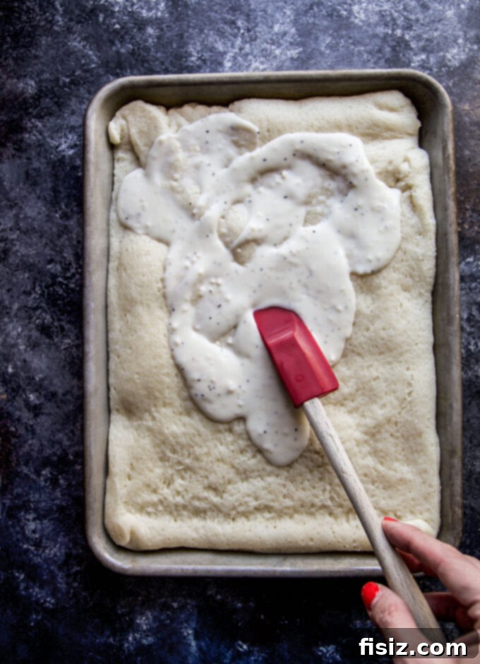 Creamy Burrata Mushroom Sheet Pan Pizza 5 Spreading creamy white garlic sauce evenly over a par-baked pizza dough on a sheet pan.