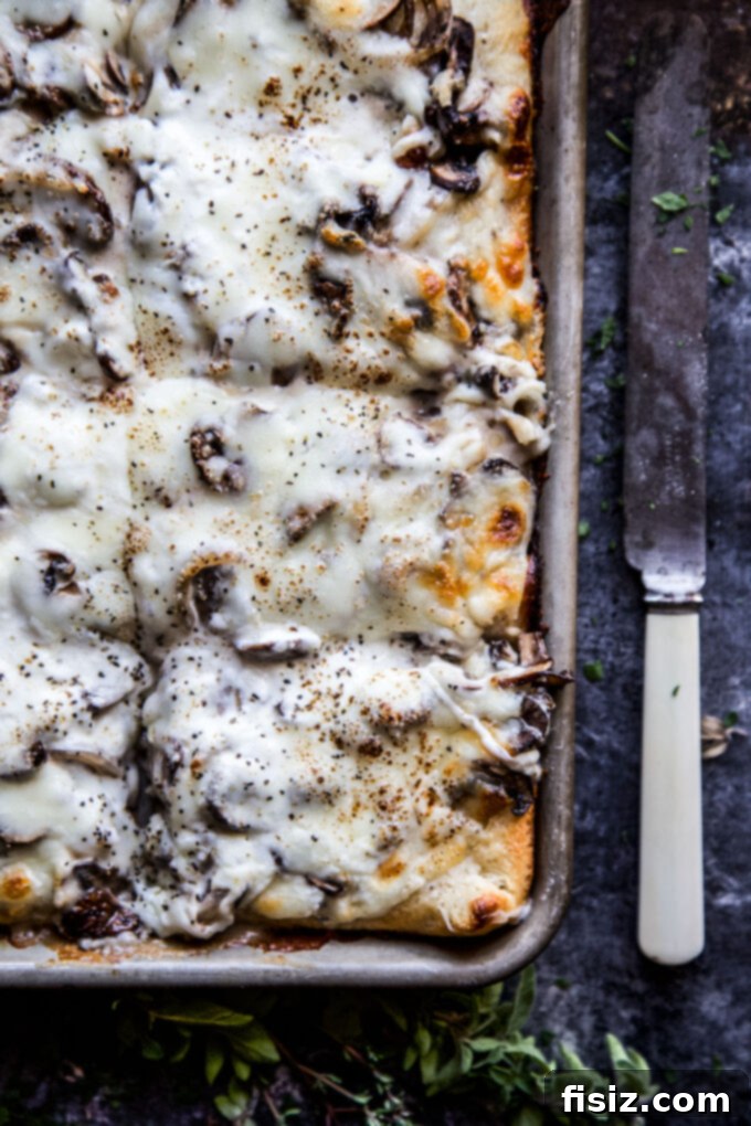 Creamy Burrata Mushroom Sheet Pan Pizza 7 A close-up of a slice of Sheet Pan Mushroom & Burrata Pizza being served, showing the melty cheese and toppings.