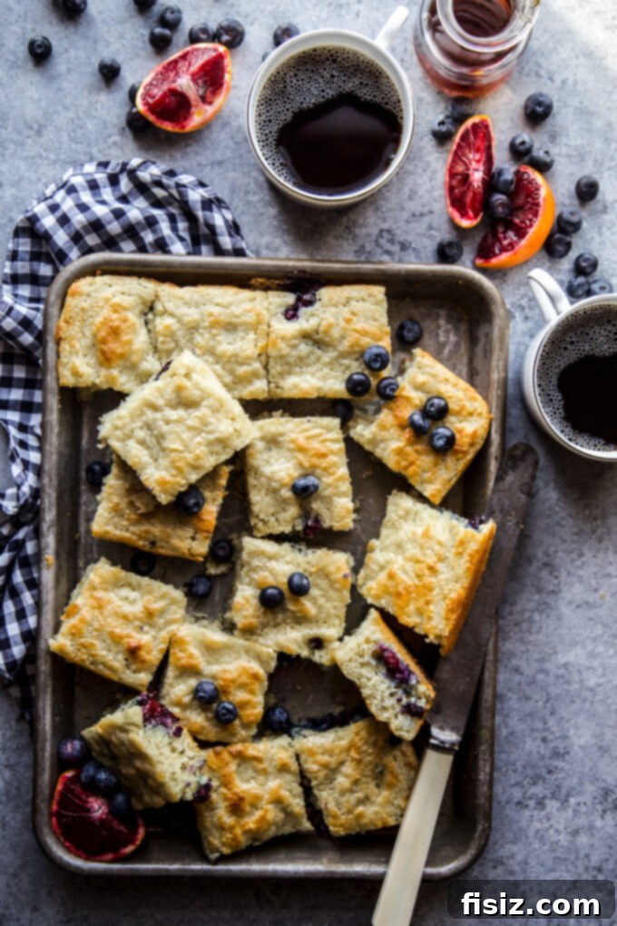 A beautifully presented slice of Blueberry & Blood Orange Sheet Pan Pancake on a white plate, ready to be enjoyed.