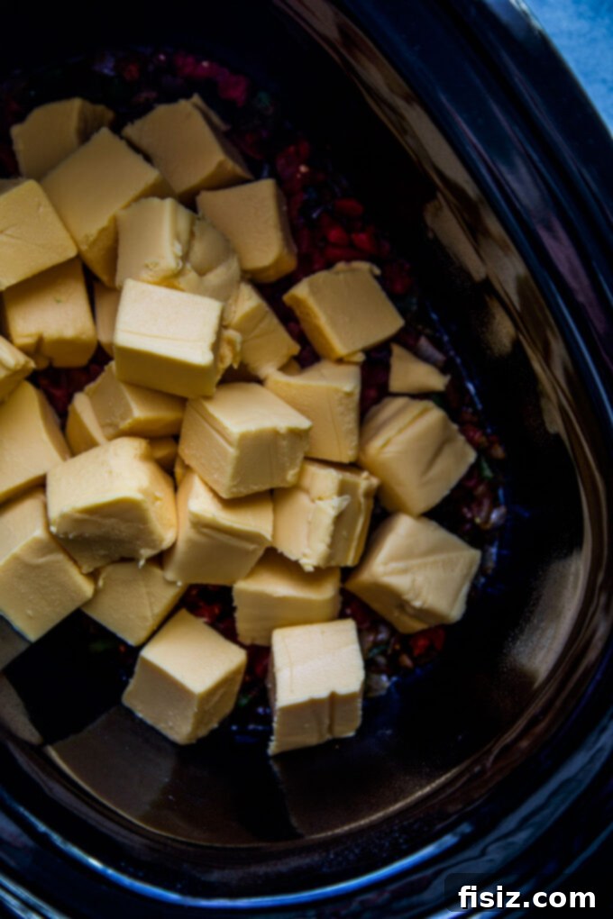 Creamy Slow Cooker Tex-Mex Queso 5 Ingredients for Tex-Mex Queso laid out on a cutting board