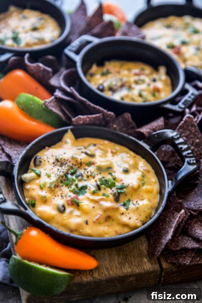 Creamy Slow Cooker Tex-Mex Queso 8 Serving bowl of slow cooker Tex-Mex queso surrounded by toppings and chips