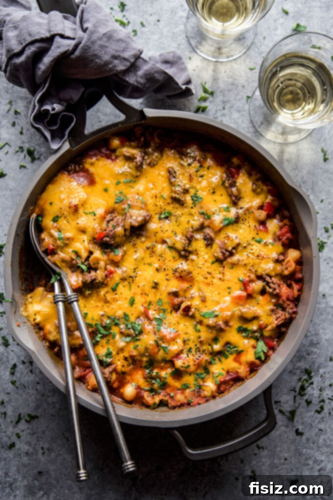 Homestyle Sloppy Joe Turkey Bake 2 Turkey Sloppy Joe Casserole in a skillet with melted cheese on top and two spoons in the pan.