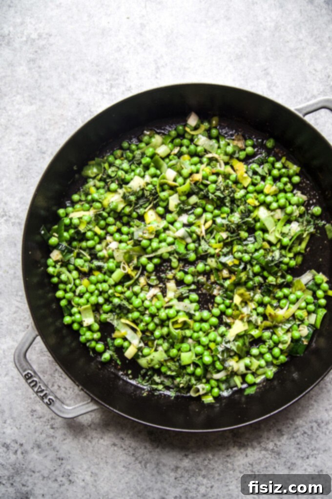 Spring-Inspired Chicken Thighs with Mint and Peas 4 Peas and leeks cooking in a skillet, gently softened and fragrant, forming the base of the sauce.