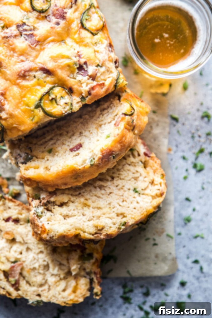 Quick Beer Cheese Bread 3 A freshly baked loaf of Easy Beer Cheese Bread, sliced to show the internal texture with chunks of cheese, bacon, and jalapeños perfectly distributed.