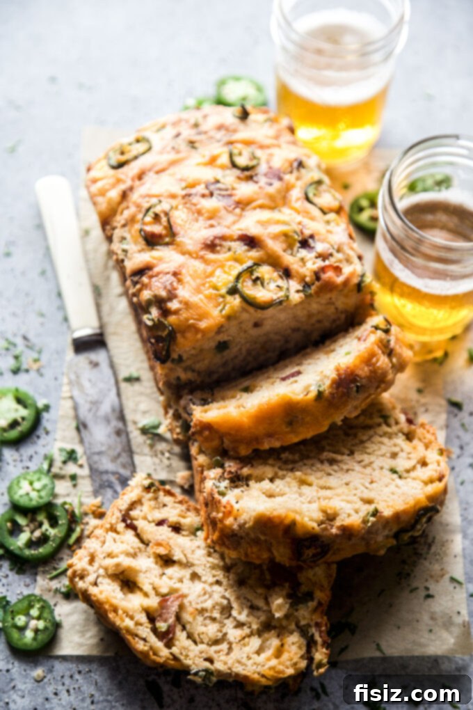 Quick Beer Cheese Bread 8 A close-up of a perfectly baked slice of Easy Beer Cheese Bread on a rustic wooden board, showcasing its rich texture, melted cheese, and visible pieces of bacon and jalapeños.