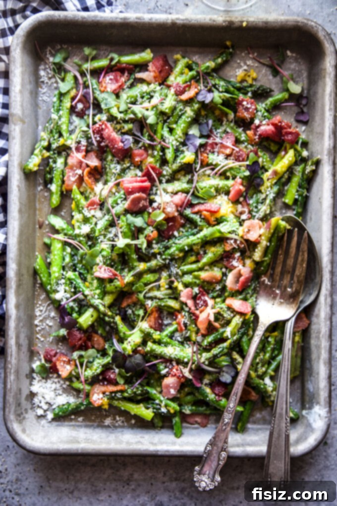 Spring Asparagus Carbonara 3 A close-up shot of pan-fried asparagus and crispy bacon sizzling together in a black skillet, forming the base of a delicious carbonara.