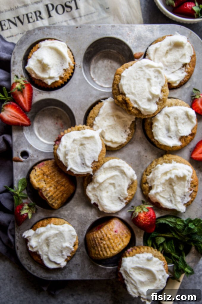 A tray of freshly baked and frosted Strawberry Banana Bread Muffins