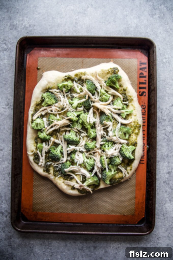 Vibrant Green Goddess Chicken Pizza 6 Adding shredded chicken and broccoli to pizza