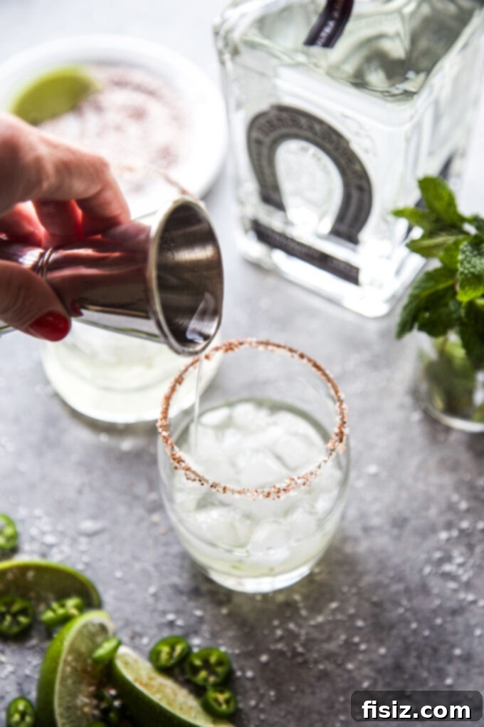 Cucumber Margarita with a Tequila Lime Jalapeño Zing 6 Hand holding a cocktail shaker, muddling fresh ingredients for a Spicy Cucumber Margarita, illustrating the preparation process.