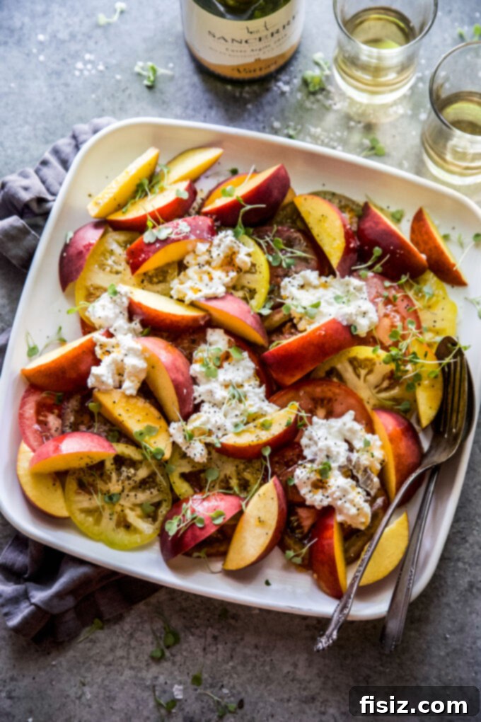 Hot Honey Burrata Salad with Peaches and Tomatoes 3 Close-up of creamy burrata cheese placed atop sliced peaches and tomatoes, drizzled with hot honey sauce.