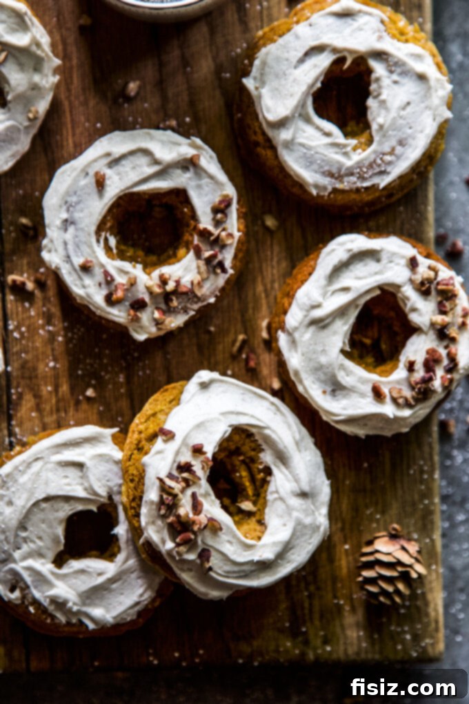 Maple Kissed Baked Pumpkin Doughnuts 3 Close-up of baked pumpkin doughnuts with maple frosting and pecans on a cooling rack