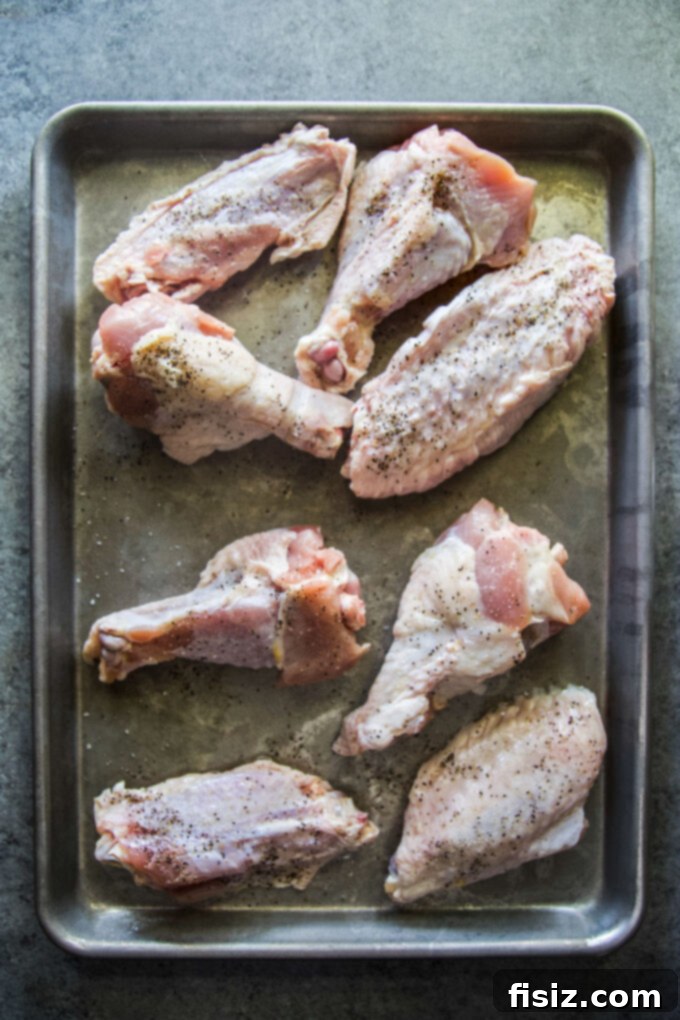 Simple Homemade Turkey Stock 4 Uncooked turkey wings on a sheet pan ready for roasting