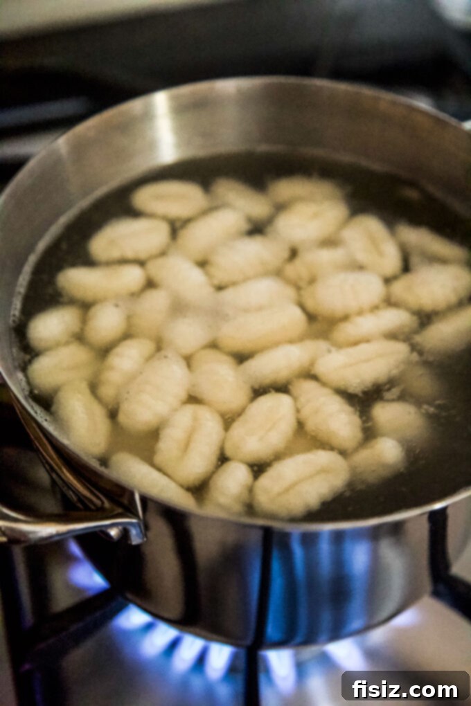 Smoky Cheddar Apple and Poblano Gnocchi Bake 8 Gnocchi boiling in a pot, with some pieces floating to the surface indicating they are cooked.