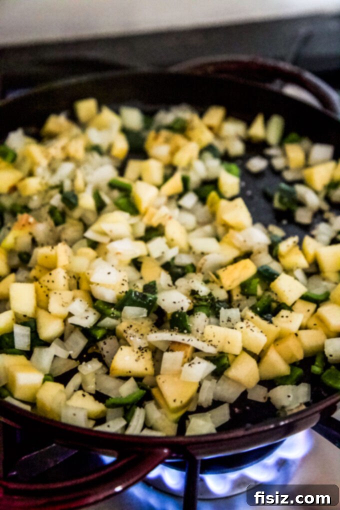 Smoky Cheddar Apple and Poblano Gnocchi Bake 9 Diced apple and poblano pepper sautéing in a skillet, turning golden.