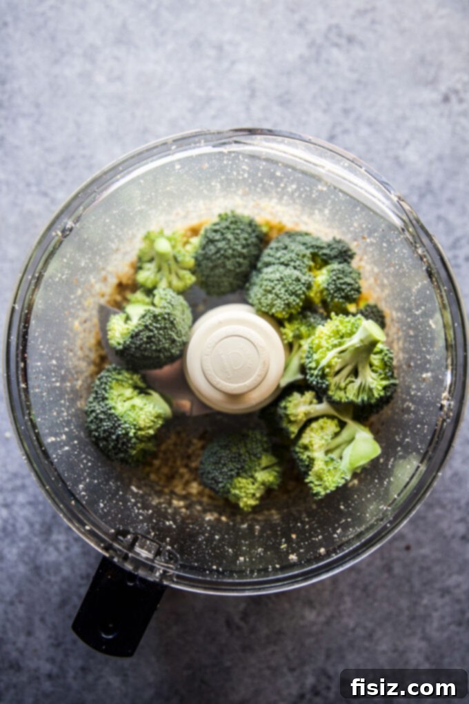 Vibrant Broccoli Walnut Pesto Pasta 5 Cooked pasta being tossed with green broccoli walnut pesto sauce in a mixing bowl
