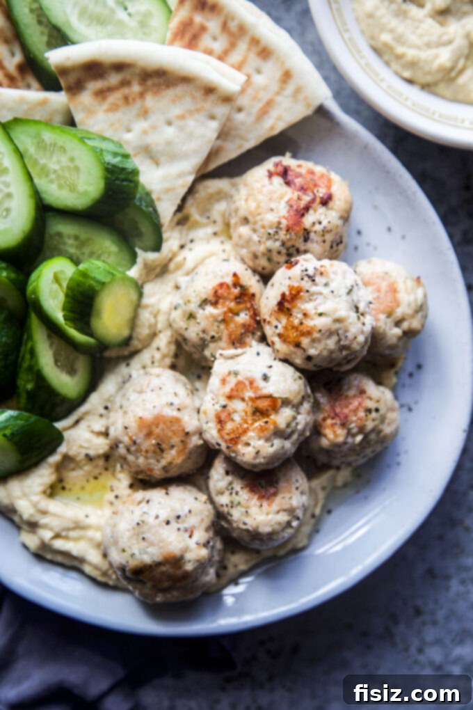 Zesty Lemon Garlic Chicken Meatballs with Creamy Hummus 3 Close-up of golden brown Garlic Lemon Chicken Meatballs on a serving platter with fresh herbs.