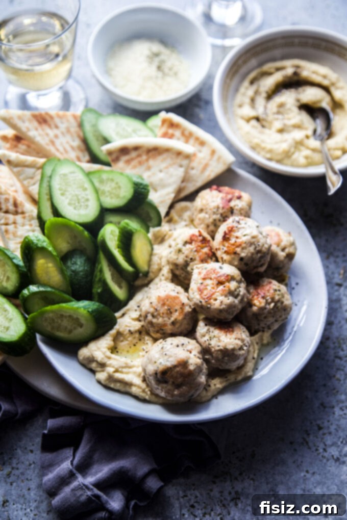 Zesty Lemon Garlic Chicken Meatballs with Creamy Hummus 8 A beautifully presented dish of Garlic Lemon Chicken Meatballs with Homemade Hummus, garnished with fresh parsley and a drizzle of olive oil.