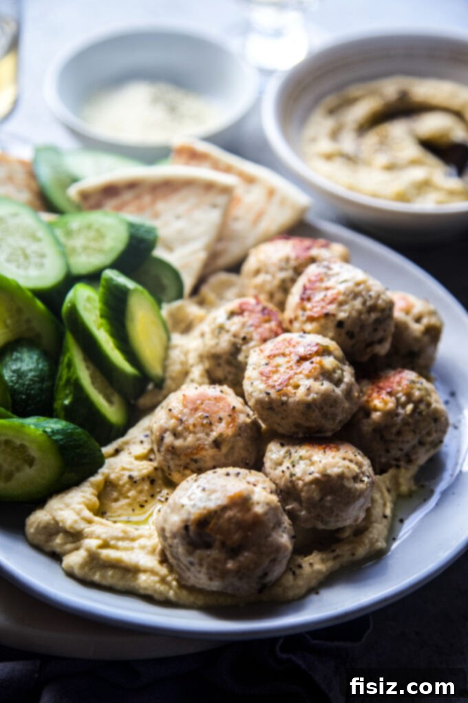 Zesty Lemon Garlic Chicken Meatballs with Creamy Hummus 10 A serving of Garlic Lemon Chicken Meatballs with Homemade Hummus, presented with toasted pita bread and fresh vegetables.