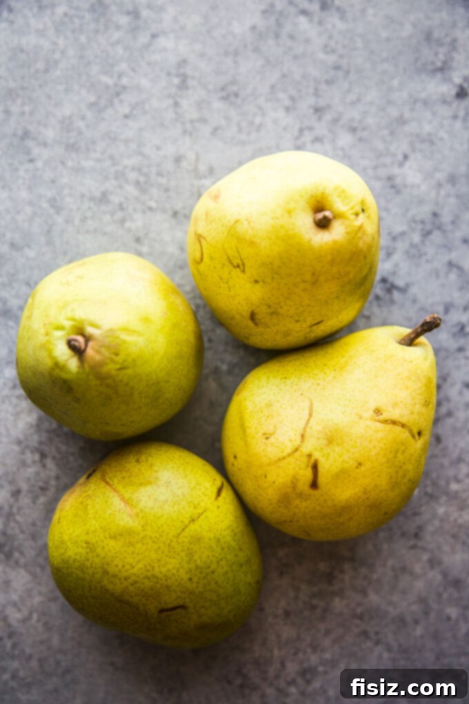 Rustic Cardamom Pear Galette 4 Fresh, ripe pears on a wooden table, ready for slicing