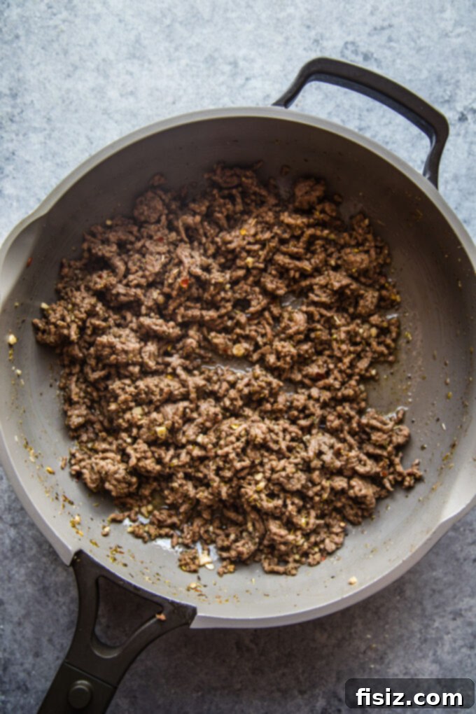 Loaded Beef Pita Nachos with Whipped Feta 4 Sautéed ground beef cooking in a skillet with aromatic spices like oregano and garlic, forming the flavorful base for the Beef Pita Nachos.
