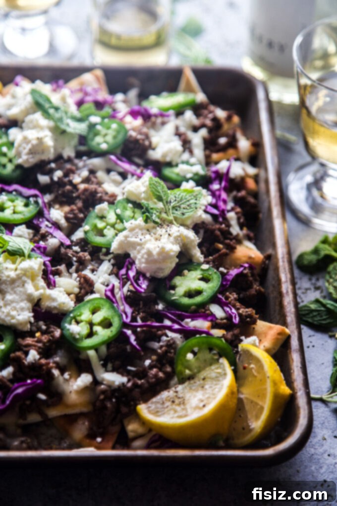 Loaded Beef Pita Nachos with Whipped Feta 5 A close-up of fully loaded Beef Pita Nachos with a generous layer of melted cheese, seasoned ground beef, and topped with fresh mint and whipped feta.