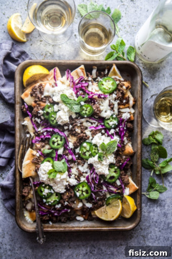 Loaded Beef Pita Nachos with Whipped Feta 8 A vibrant platter of fully garnished Beef Pita Nachos, showcasing the colorful array of fresh toppings like mint, red cabbage, and a generous dollop of creamy whipped feta.