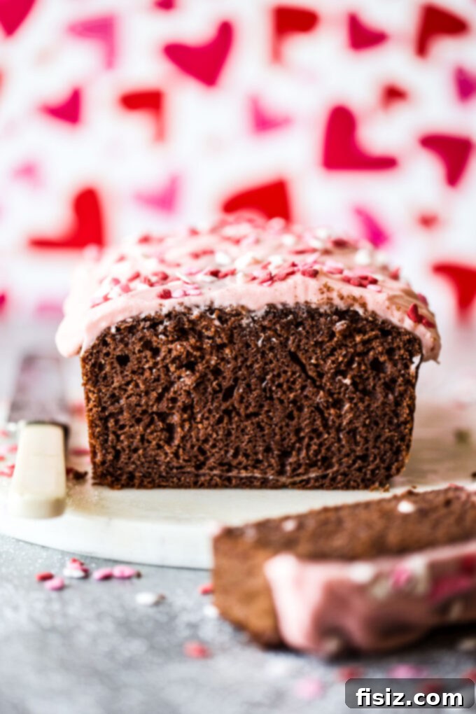 Delicious chocolate loaf cake generously topped with vibrant cherry frosting, captured from www.thecuriousplate.com