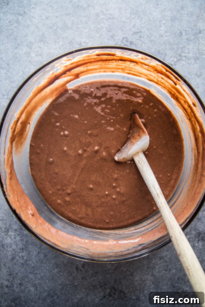 Chocolate cake mix being prepared in a large mixing bowl, ready for baking.