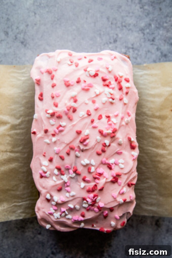 The finished chocolate loaf cake, beautifully frosted with cherry frosting and adorned with heart sprinkles.