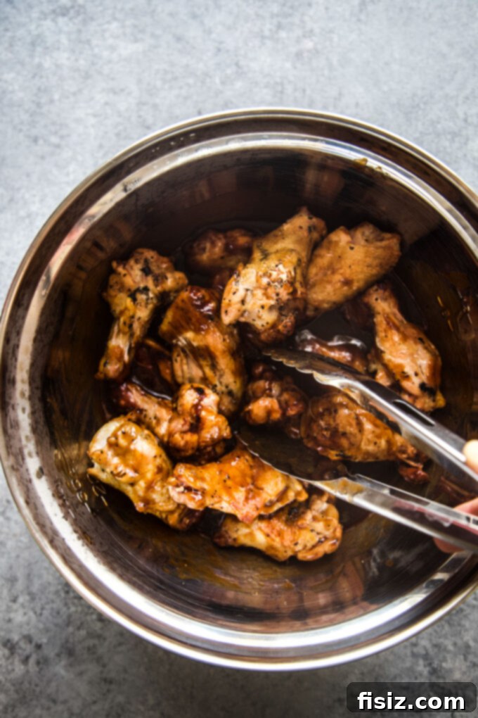 Smoky Gochujang Wings 6 Smoked Korean-Style Hot Wings being tossed with the sticky sauce