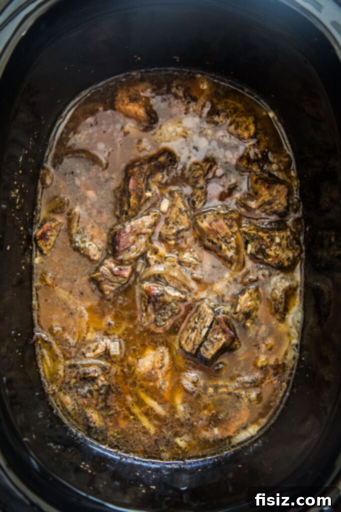 Fall-Apart Tender Slow Cooker Pot Roast Sandwiches 6 Slow cooker filled with beef and onions after 8 hours of cooking, before shredding.