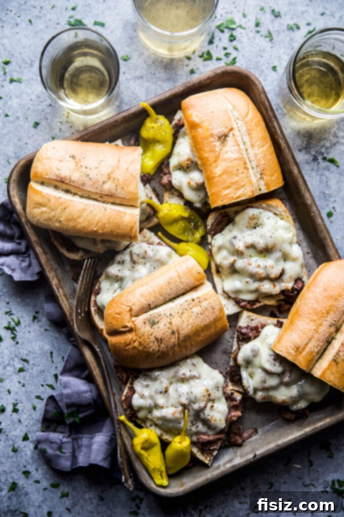 Fall-Apart Tender Slow Cooker Pot Roast Sandwiches 10 Two fully assembled shredded pot roast sandwiches on a cutting board, garnished with fresh herbs.