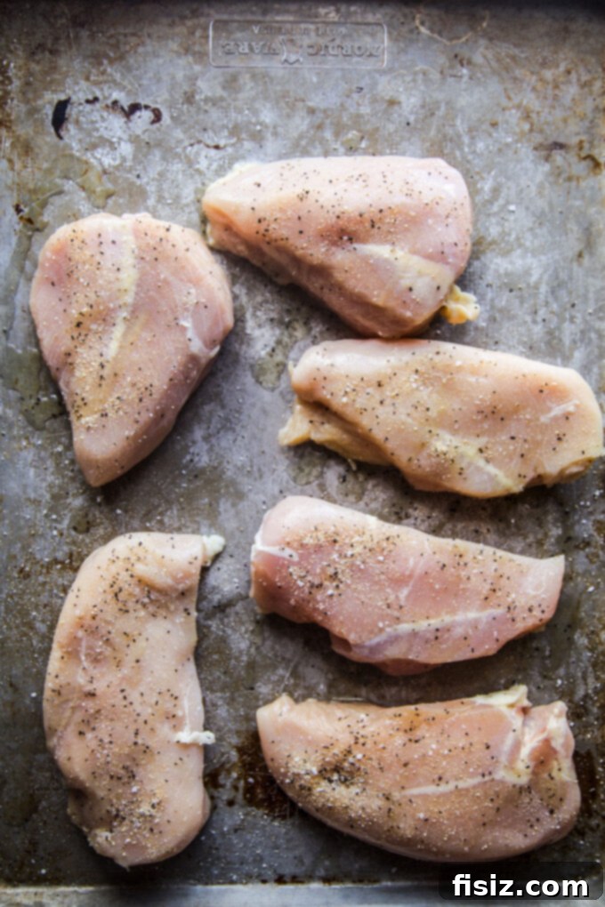 Sweet Heat Strawberry-Jalapeño Chicken 4 Raw chicken breasts seasoned on a baking sheet, ready for cooking.