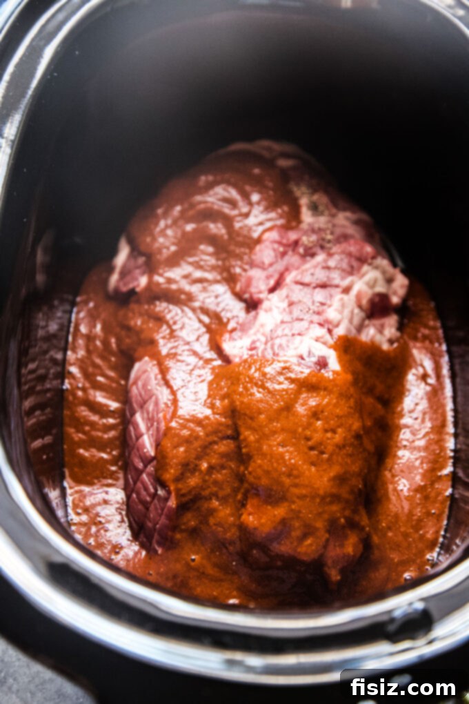 Melt-in-Your-Mouth Slow Cooker Al Pastor Lamb Tacos 10 Lamb shoulder fully covered with the vibrant Al Pastor sauce in the slow cooker, ready to cook