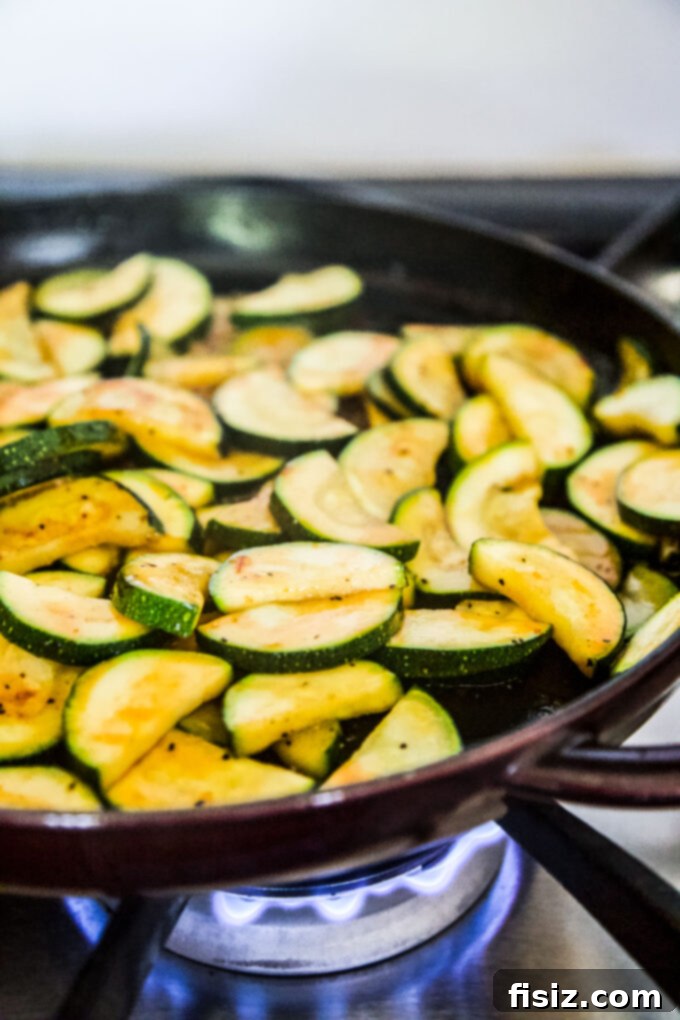 Chili Crisp Zucchini Sizzle 6 Close-up of golden-brown spiced zucchini slices in a skillet, coated with sauce.