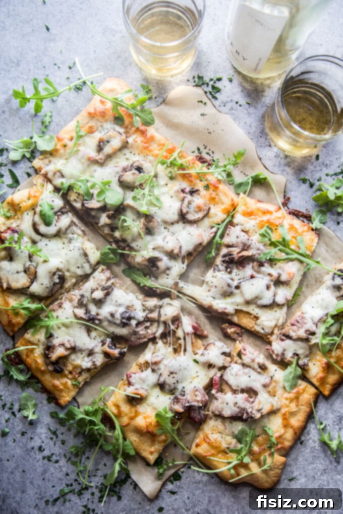 Cowboy Butter Steakhouse Pizza 2 cowboy butter steak pizza on a cutting board, garnished with fresh arugula